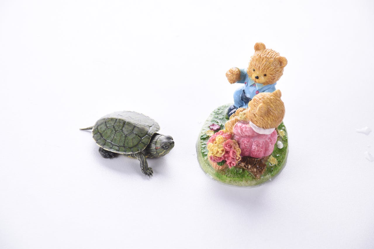 Whimsical scene with teddy bear figures and a small turtle figurine on a white background.