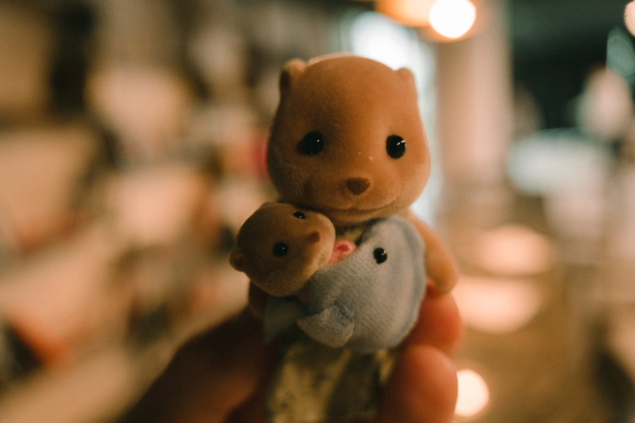 Close-up of a small teddy bear toy held in a persons hand indoors.