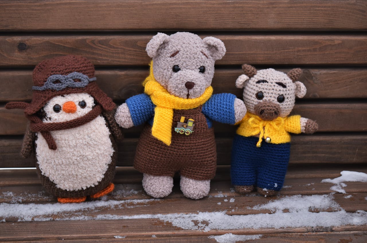 Amigurumi crochet toys placed on a snowy wooden bench. Perfect for winter and craft themes.